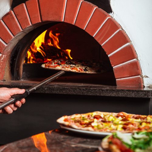 the chef takes pizza. Italian pizza is cooked in a wood-fired oven